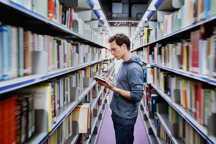 Etudiant lisant un livre à la bibliothèque